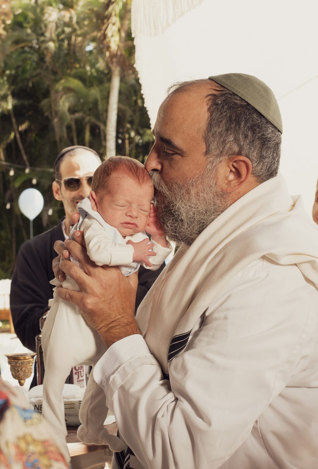 Rabbi Yossi tenderly kissing a newborn baby's head